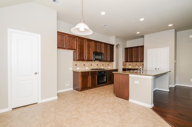 kitchen featuring visible vents, black appliances, stone countertops, tasteful backsplash, and arched walkways