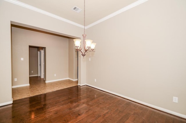 spare room featuring visible vents, an inviting chandelier, wood finished floors, and ornamental molding