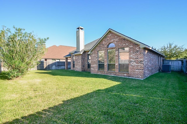 rear view of property featuring a yard, brick siding, and fence