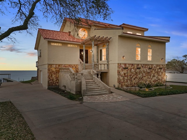 mediterranean / spanish home with stairs, a tile roof, driveway, and stucco siding