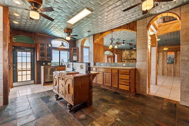 kitchen with a sink, dishwasher, ceiling fan, and brown cabinetry