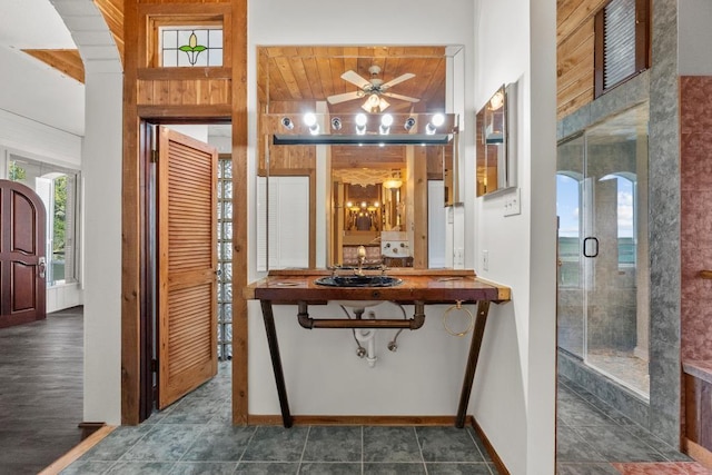 full bath with ceiling fan, a shower stall, baseboards, and a sink