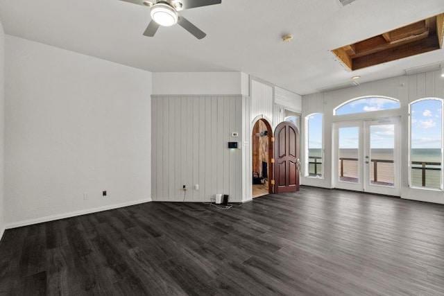 unfurnished living room with a ceiling fan, dark wood finished floors, french doors, a skylight, and baseboards