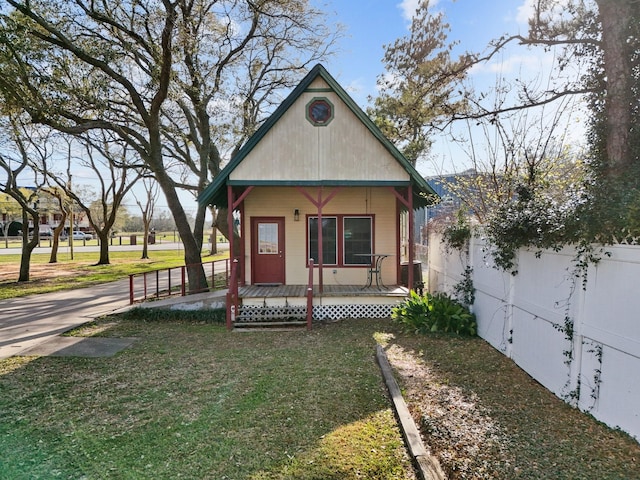 view of front facade with a porch, a front lawn, and fence