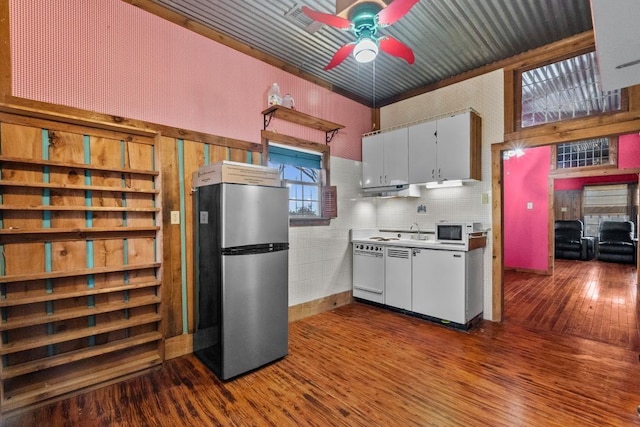 kitchen featuring white microwave, dark wood-type flooring, ceiling fan, dishwashing machine, and freestanding refrigerator