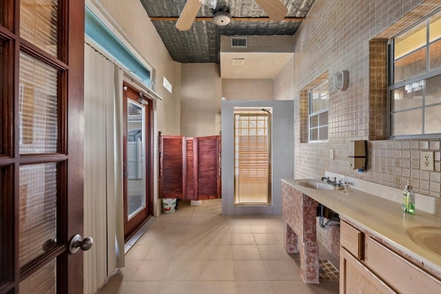 full bathroom featuring tile patterned flooring, visible vents, ceiling fan, double vanity, and a sink