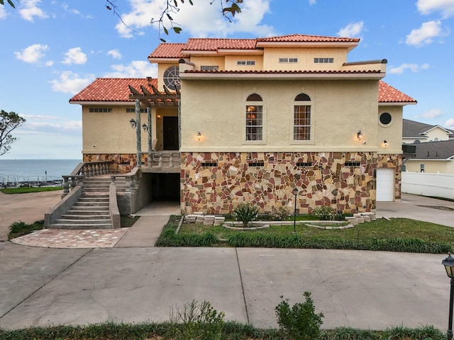 mediterranean / spanish home with a tiled roof, stone siding, and stucco siding