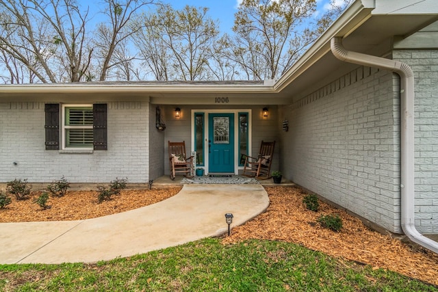 property entrance with brick siding and covered porch