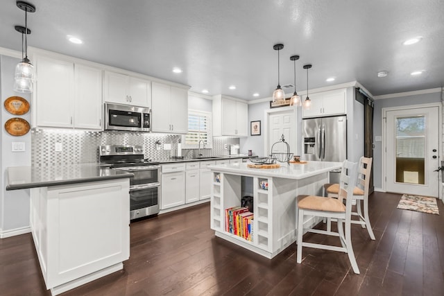 kitchen featuring a sink, white cabinetry, appliances with stainless steel finishes, a breakfast bar area, and crown molding