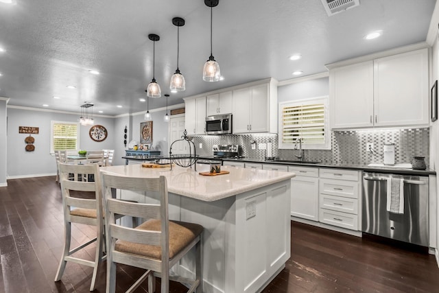 kitchen with visible vents, ornamental molding, a sink, dark wood finished floors, and stainless steel appliances