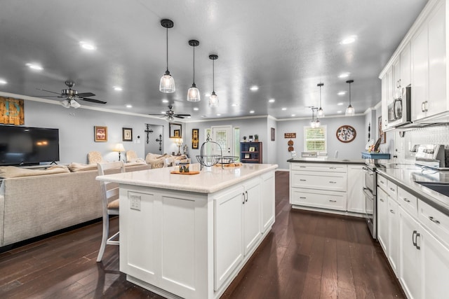 kitchen with open floor plan, stainless steel appliances, a peninsula, ceiling fan, and dark wood-style flooring