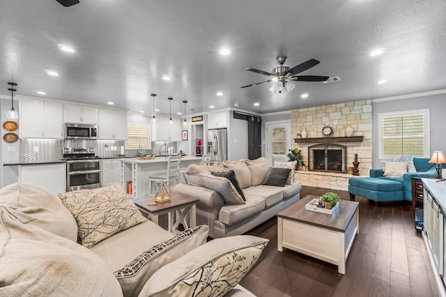 living room with a healthy amount of sunlight, a textured ceiling, ceiling fan, and dark wood-style flooring