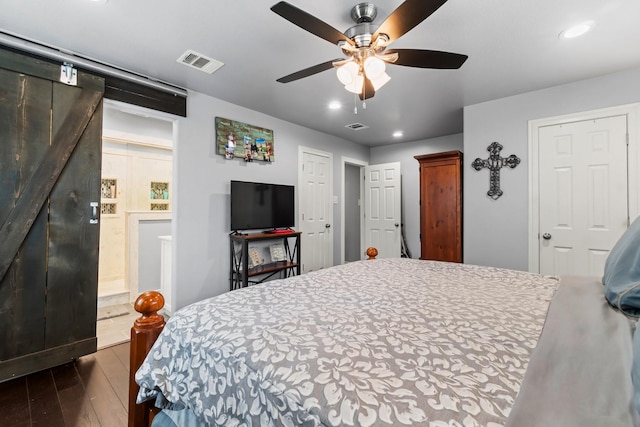 bedroom with recessed lighting, visible vents, a barn door, and wood finished floors