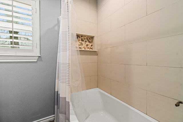 bathroom with shower / tub combo and a textured wall