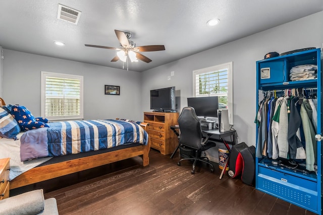 bedroom featuring visible vents, multiple windows, ceiling fan, and wood finished floors