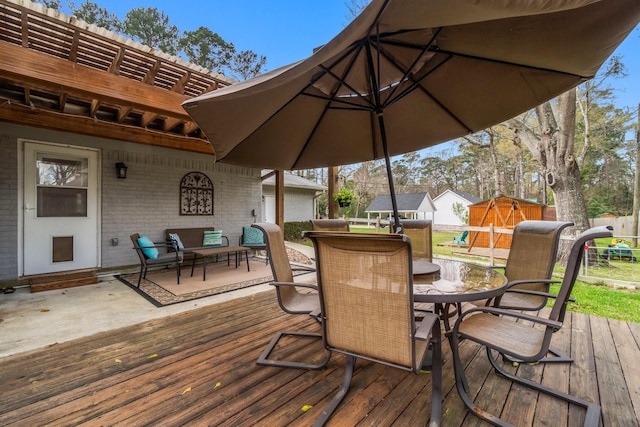 deck with an outbuilding, a storage unit, outdoor dining area, and fence