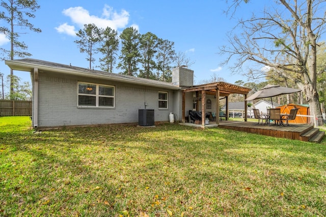 back of property with a yard, brick siding, a chimney, and fence