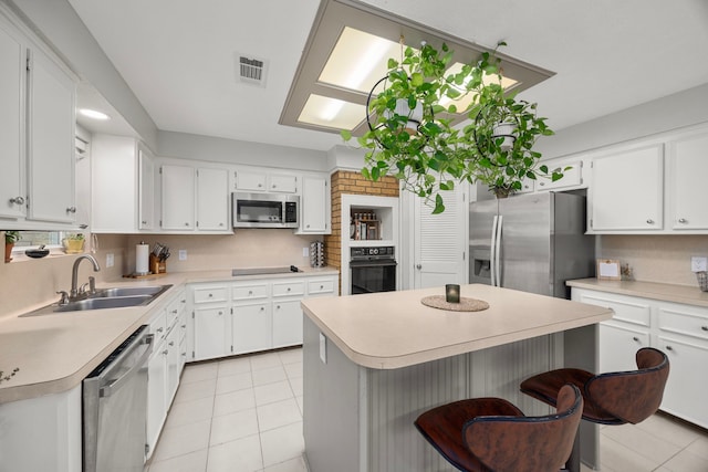 kitchen featuring visible vents, light countertops, decorative backsplash, black appliances, and a sink