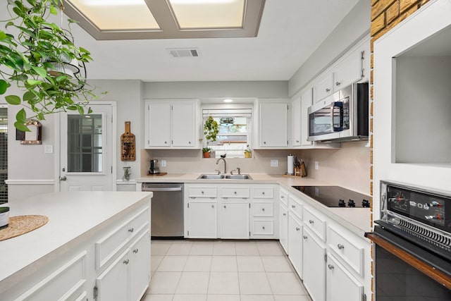 kitchen featuring visible vents, black appliances, a sink, white cabinetry, and light countertops