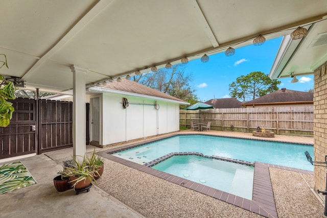 view of pool with an outbuilding, a pool with connected hot tub, a patio, and fence