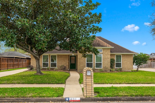 view of front of property with brick siding, roof with shingles, a front lawn, and fence