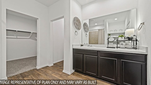 full bathroom with wood finished floors, recessed lighting, baseboards, a spacious closet, and vanity