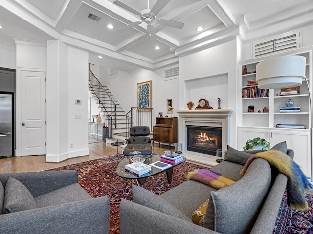 living area with visible vents, a ceiling fan, coffered ceiling, wood finished floors, and stairs