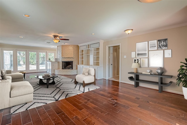 living area with a fireplace, wood finished floors, a ceiling fan, and ornamental molding