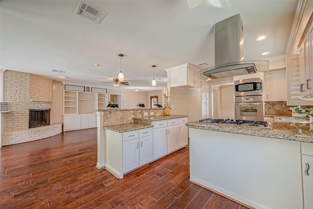 kitchen featuring visible vents, open floor plan, stainless steel appliances, a peninsula, and island range hood