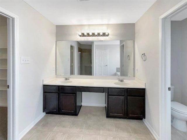 bathroom with a sink, baseboards, toilet, and double vanity