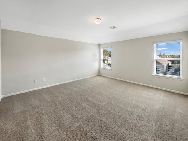 carpeted spare room with visible vents and baseboards