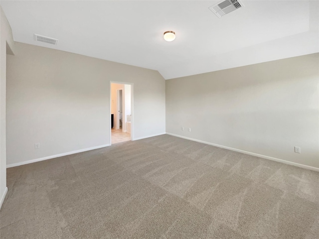 carpeted spare room featuring visible vents, lofted ceiling, and baseboards