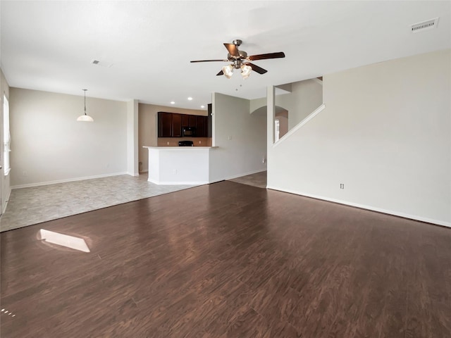 unfurnished living room featuring visible vents, wood finished floors, arched walkways, and ceiling fan