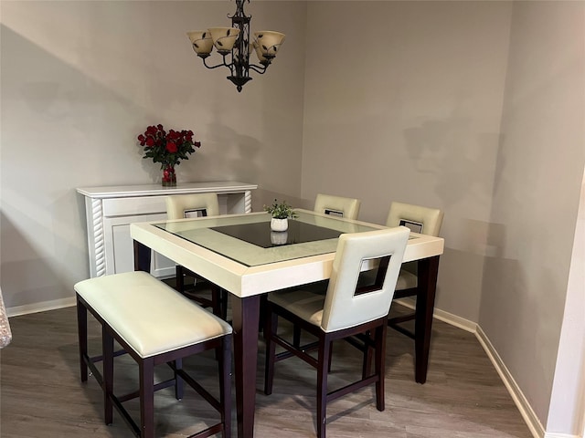 dining room featuring a notable chandelier, baseboards, and wood finished floors