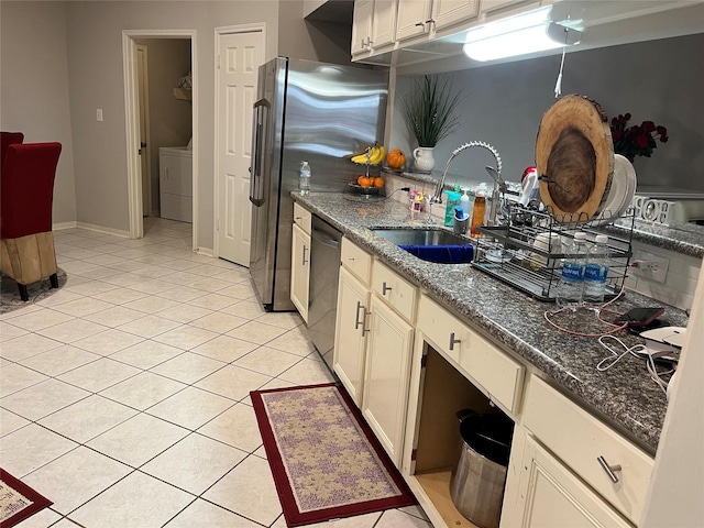 kitchen with light tile patterned floors, washer / dryer, stainless steel appliances, and a sink