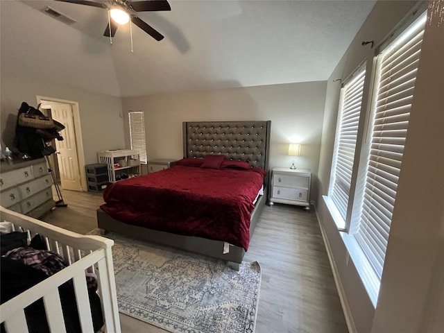 bedroom with visible vents, baseboards, lofted ceiling, wood finished floors, and a ceiling fan