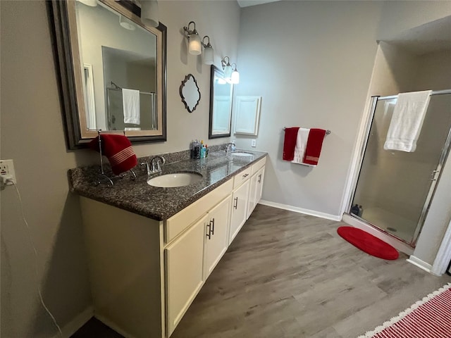 full bathroom featuring a shower stall, wood finished floors, double vanity, and a sink