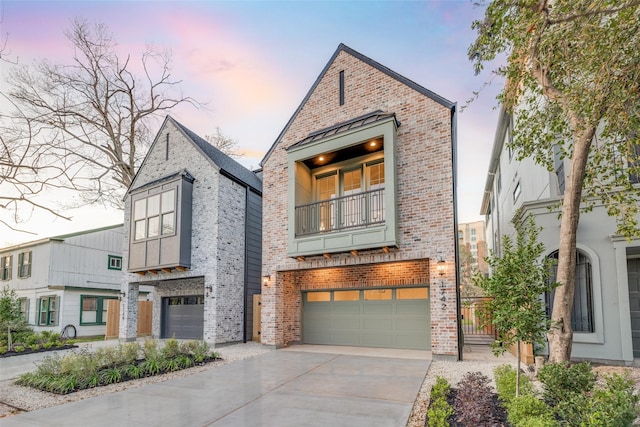 view of front facade featuring a balcony, a standing seam roof, an attached garage, concrete driveway, and brick siding