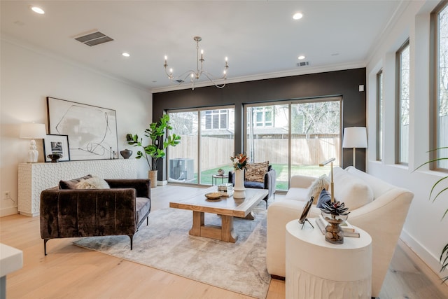 living area with a chandelier, crown molding, and light wood-style floors