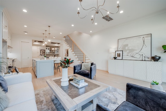 living area with stairway, recessed lighting, light wood finished floors, and a chandelier