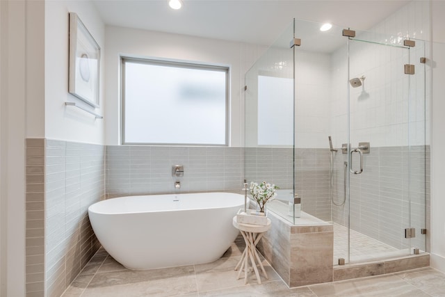 full bath with tile walls, a freestanding tub, recessed lighting, and a stall shower