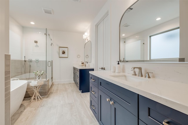 bathroom featuring visible vents, two vanities, a stall shower, a freestanding tub, and a sink