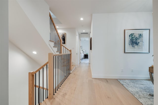 corridor with recessed lighting, stairway, baseboards, and light wood-style floors