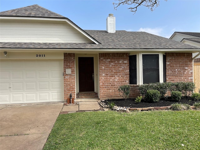 ranch-style home featuring a shingled roof, a front yard, an attached garage, brick siding, and a chimney