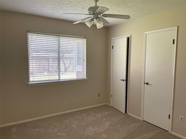 unfurnished bedroom featuring carpet, ceiling fan, and a textured ceiling