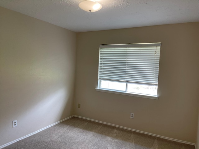 carpeted spare room with baseboards and a textured ceiling