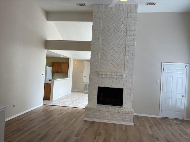 unfurnished living room featuring visible vents, a high ceiling, and a ceiling fan