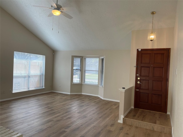 entrance foyer featuring a wealth of natural light, a textured ceiling, lofted ceiling, and wood finished floors