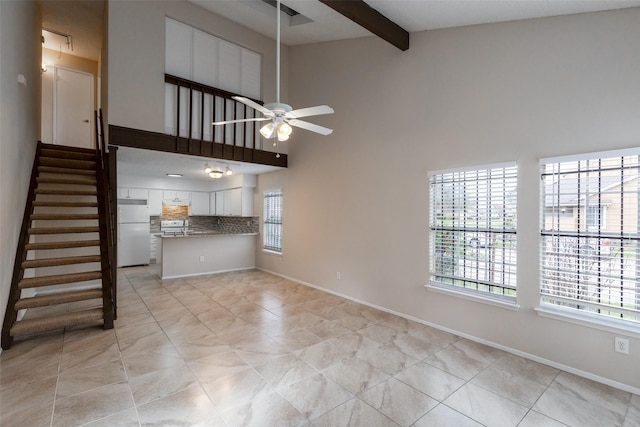 unfurnished living room with a wealth of natural light, baseboards, beam ceiling, and ceiling fan