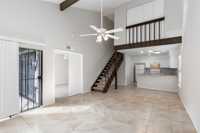 unfurnished living room with visible vents, baseboards, ceiling fan, lofted ceiling with beams, and stairs